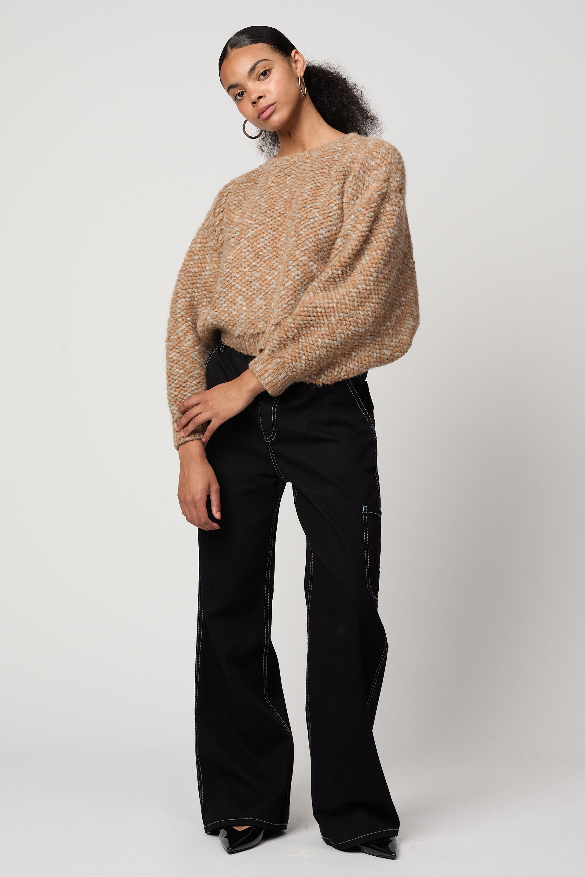 Assorted Atelier Delphine archive pieces in neutral tones, on a model standing.